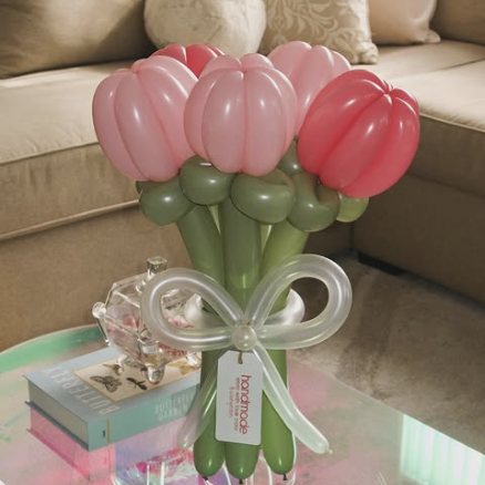 Pink balloon tulips in a glass vase with a clear balloon bow.